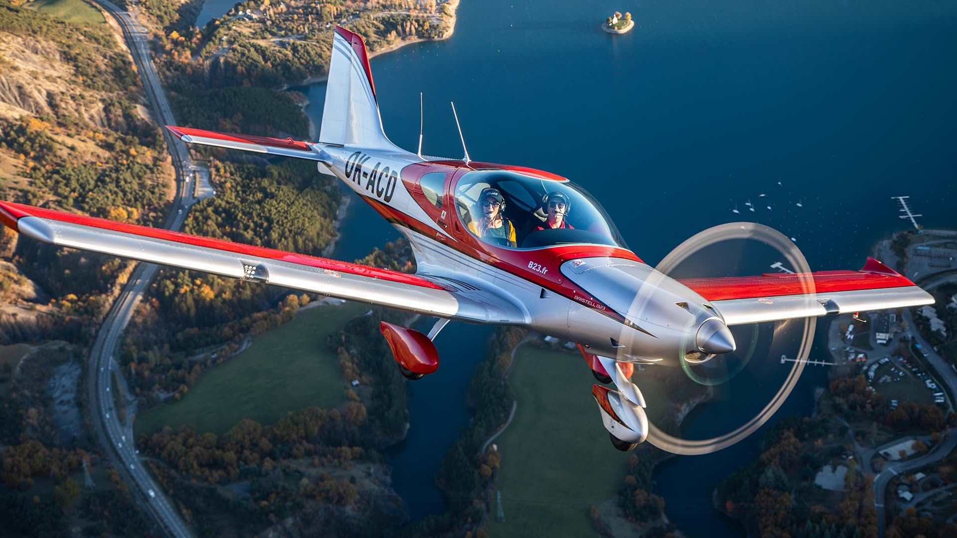 Bristell B23 Turbo in flight over a lake at golden hour